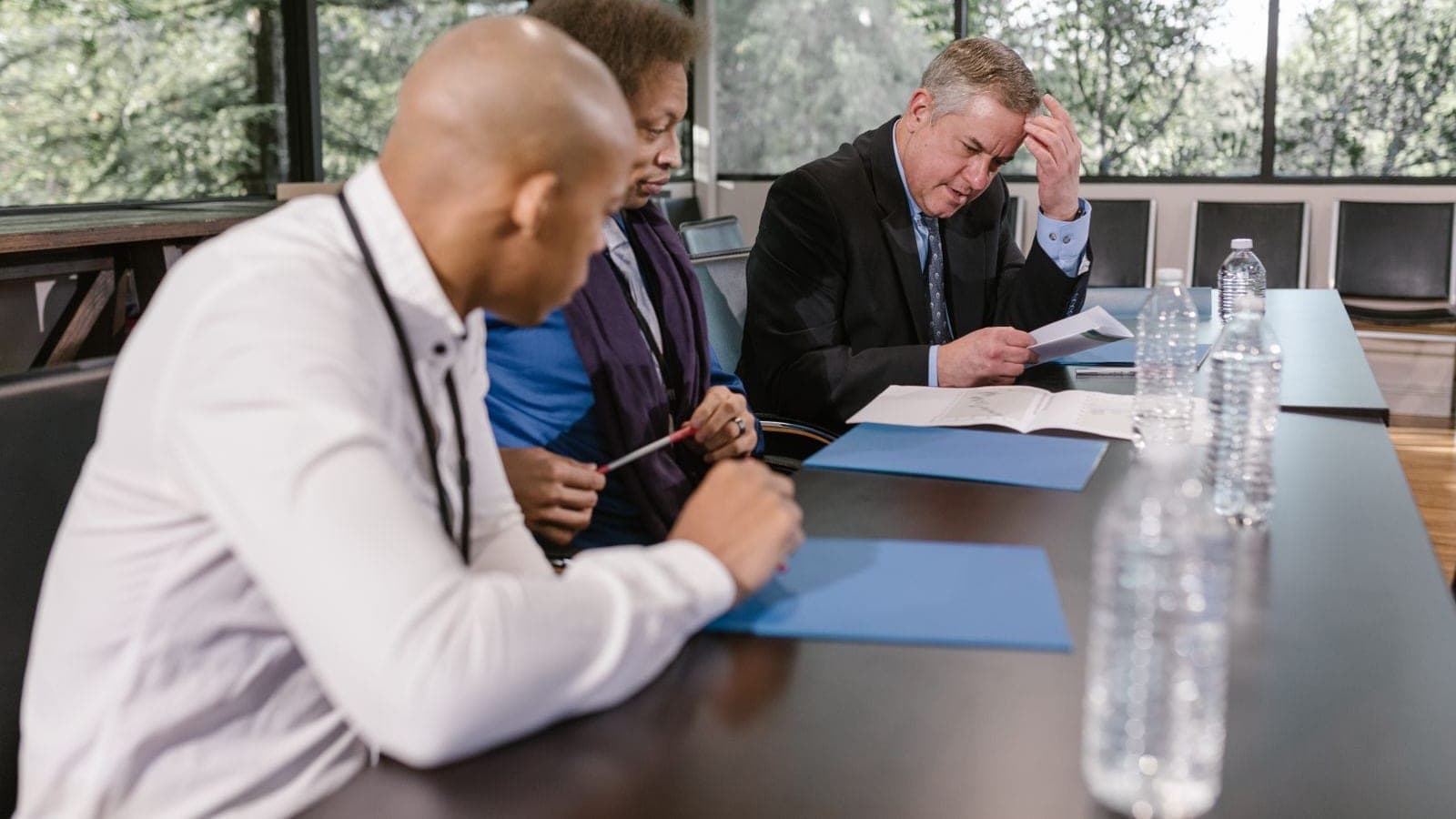 Agency team and client reviewing printed project records across a meeting table
