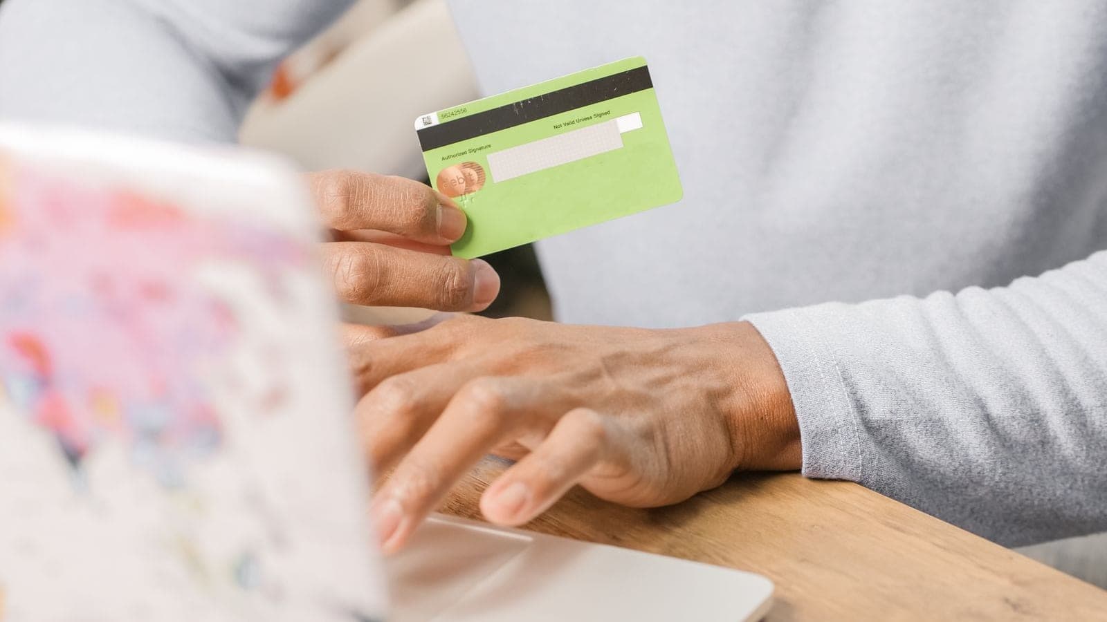 Hands holding a credit card while buying a licensed asset on a laptop