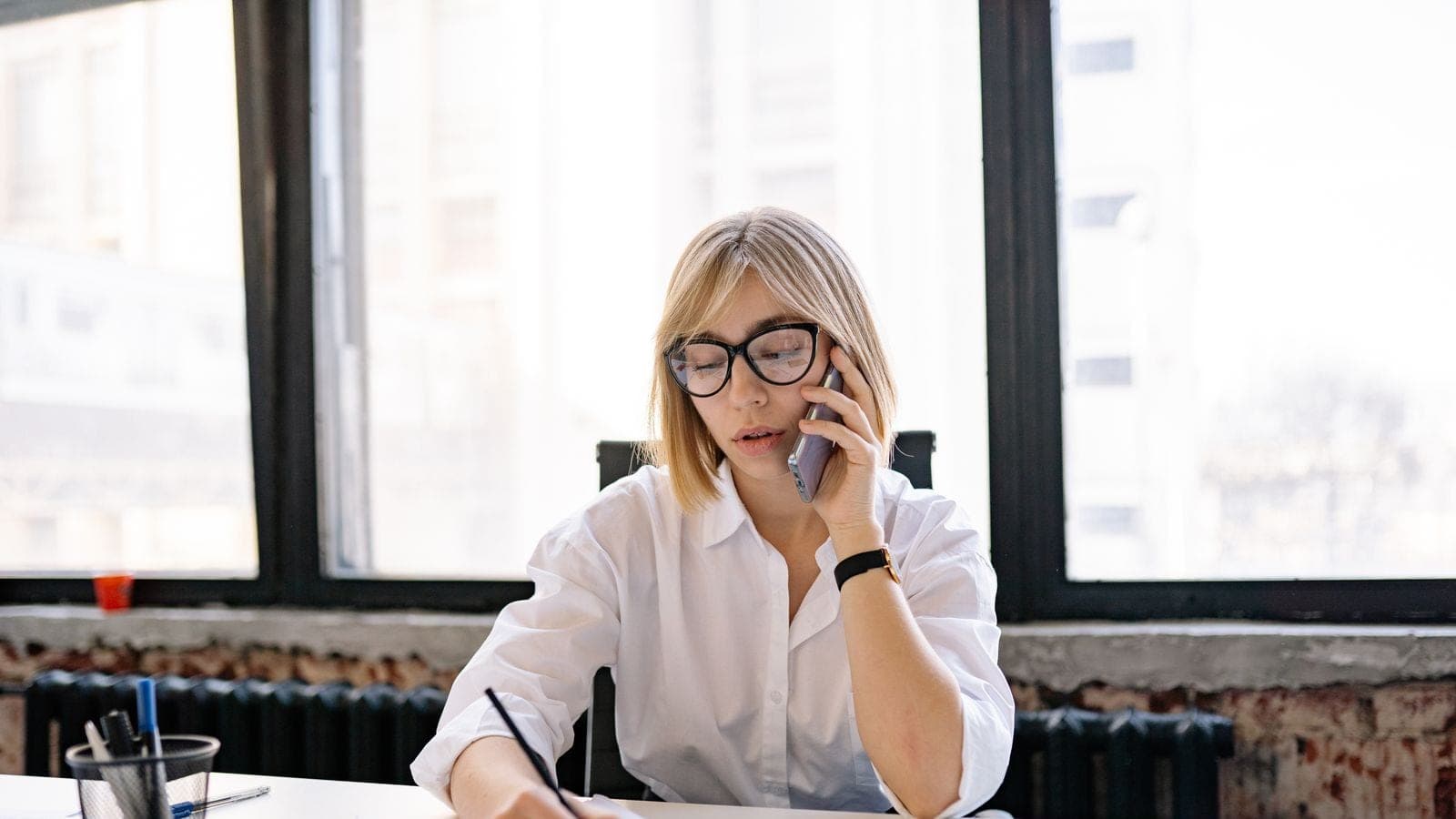 Account manager taking notes during a client phone call, with no shared record to check