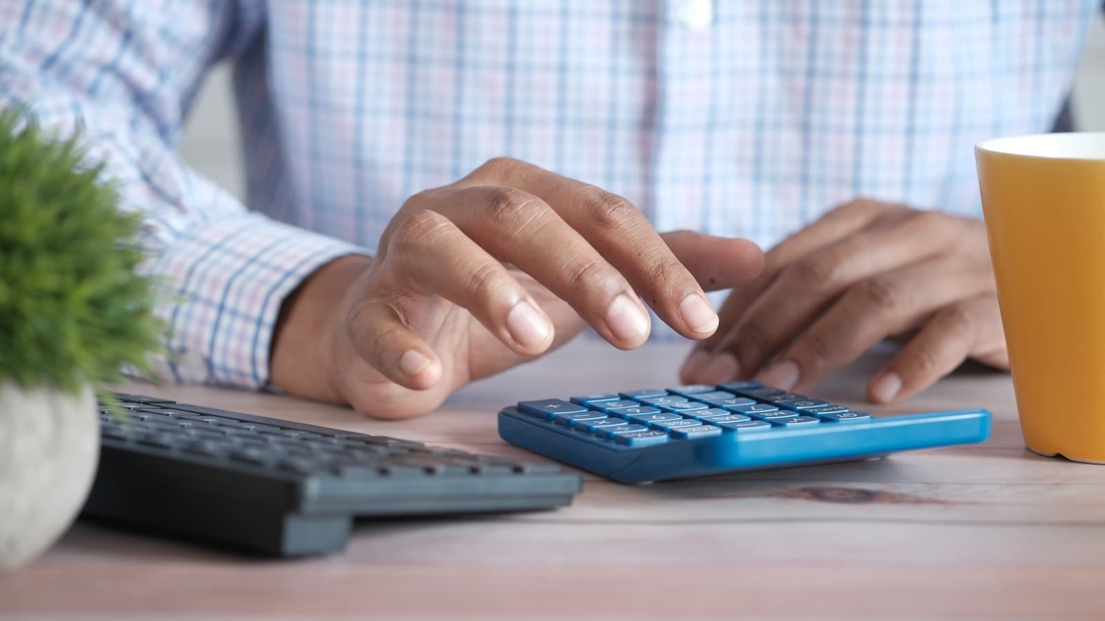 Person working out an agency billing rate on a calculator next to a keyboard at a desk