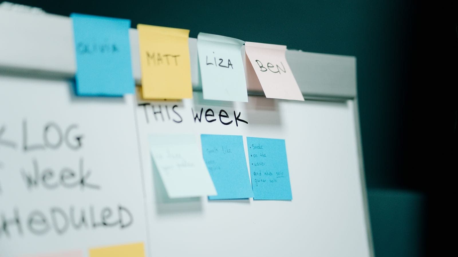 Whiteboard with hand-written Backlog, This Week and Scheduled columns and sticky notes under each