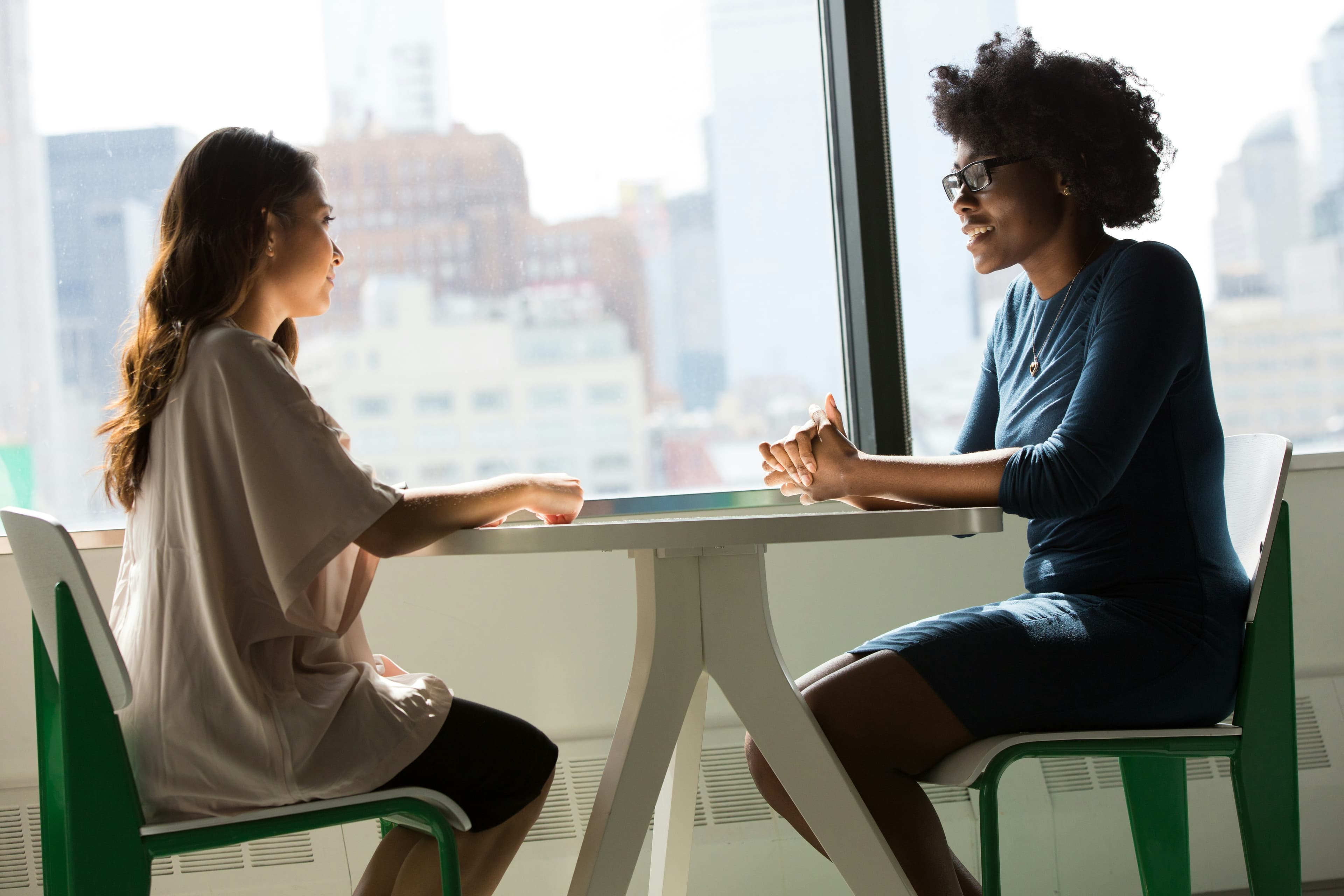 Two people having a professional pricing conversation across a desk in a business meeting