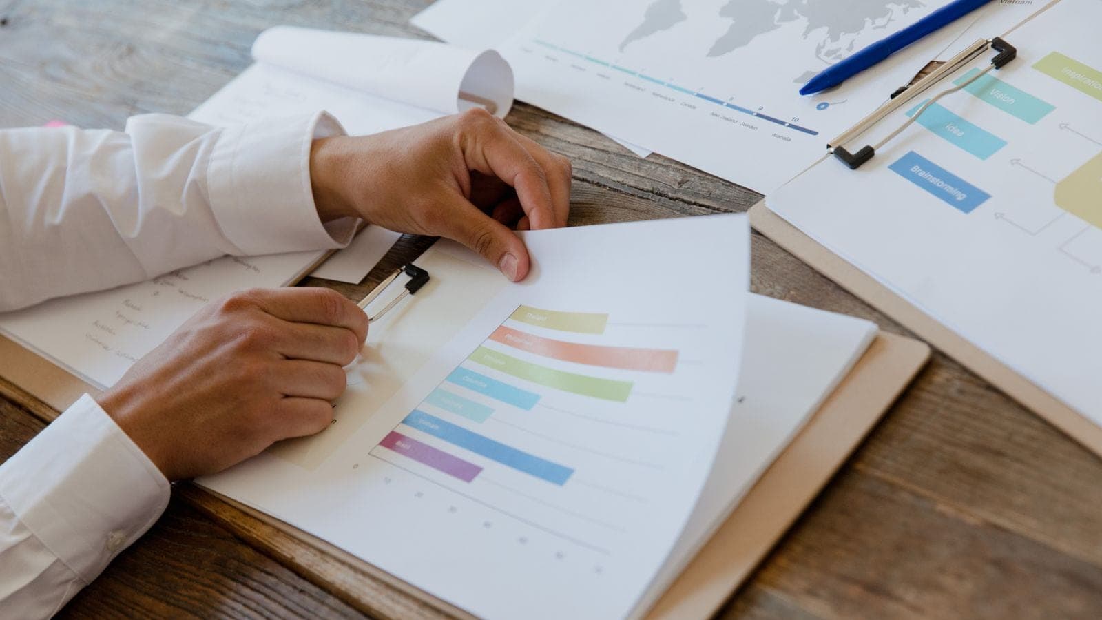 Hands reviewing a printed report of hours per project with horizontal bar charts